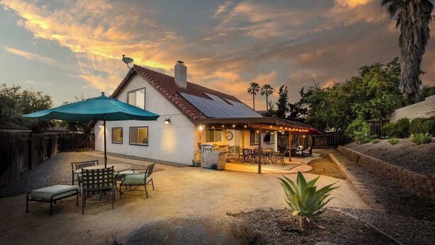 A house with a patio, outdoor seating, and a covered area with string lights. - 5 Bedroom Home With Firepit (San Diego)