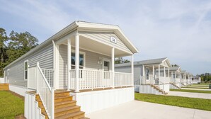 A row of white mobile homes with a porch and wooden steps, numbered 34.