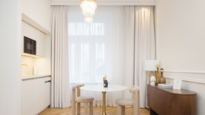 A modern dining area with a round table, four chairs, a wooden cabinet, and a television on the wall. - RAFAEL KAISER - Signature Apartments  (Vienna)