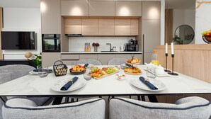 A modern kitchen with built-in appliances, a dining area with a marble table, and a breakfast spread. - Villa Evita Zadarvillas (Škabrnja)