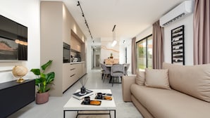 A modern apartment with a kitchen, dining area, and living room. There is a sofa, a coffee table, and a plant. - Villa Evita Zadarvillas (Škabrnja)