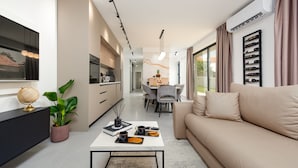 A modern living room with a sofa, coffee table, and a dining area with chairs and a table. - Villa Evita Zadarvillas (Škabrnja)