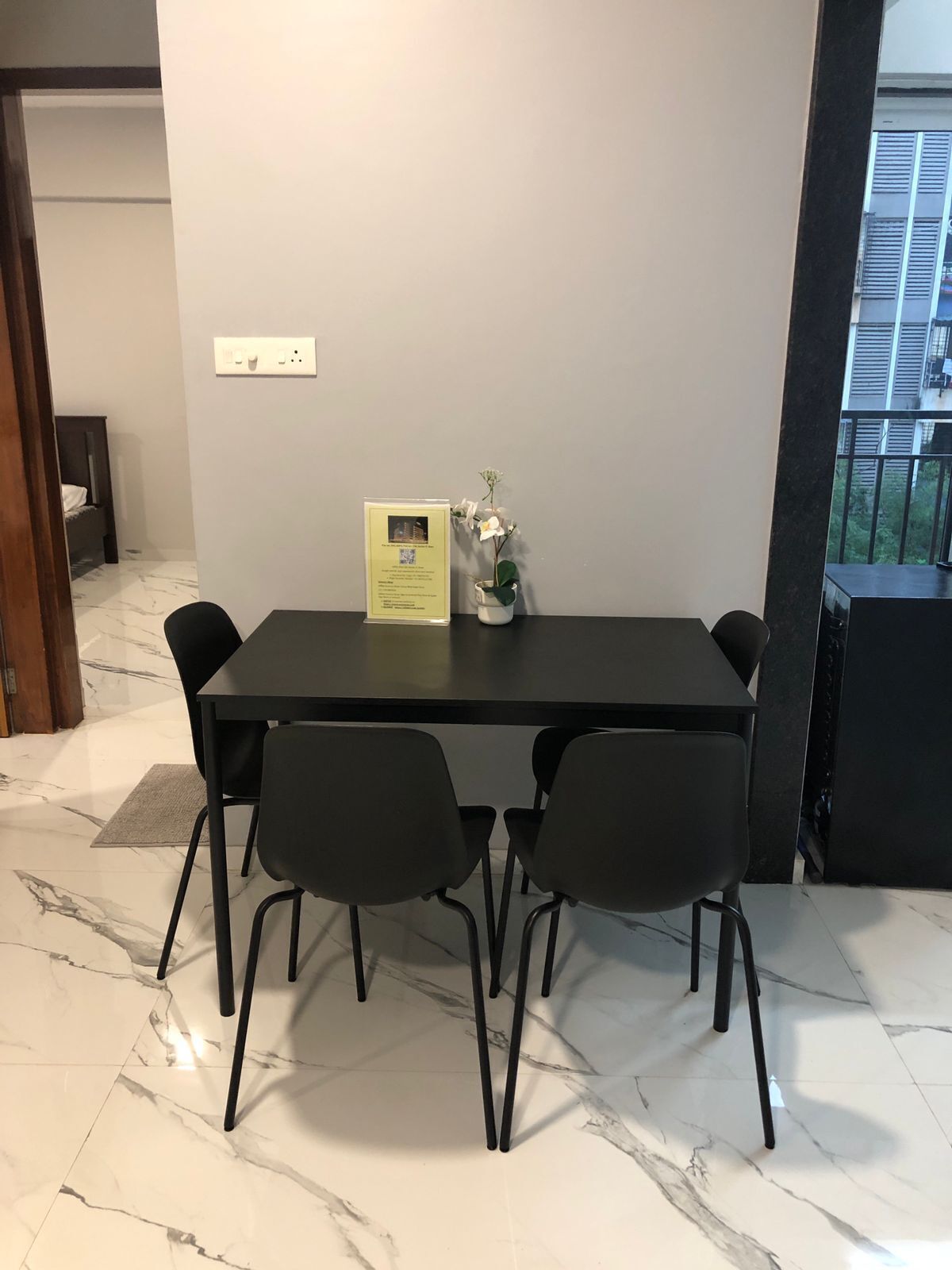 Een moderne eethoek met een marmeren vloer, een donker houten tafel en zwarte stoelen.
