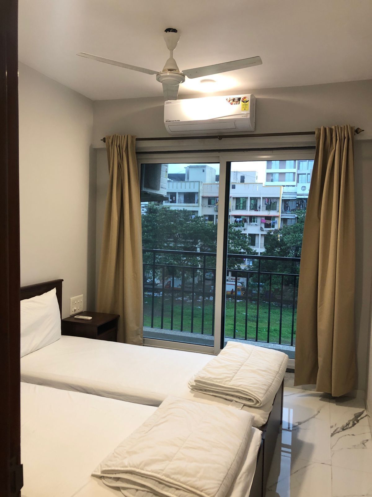 Una camera d'albergo con un letto, un comodino, una ventola a soffitto e vista sull'esterno.