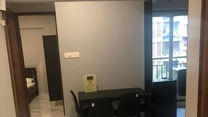 A modern interior with a marble floor, a dining area with black chairs, a small table, and a view of buildings through a window. - ASPA-Home Away From Home. Spacious, Comfortable, Safe & Neat apartments. (Navi Mumbai)