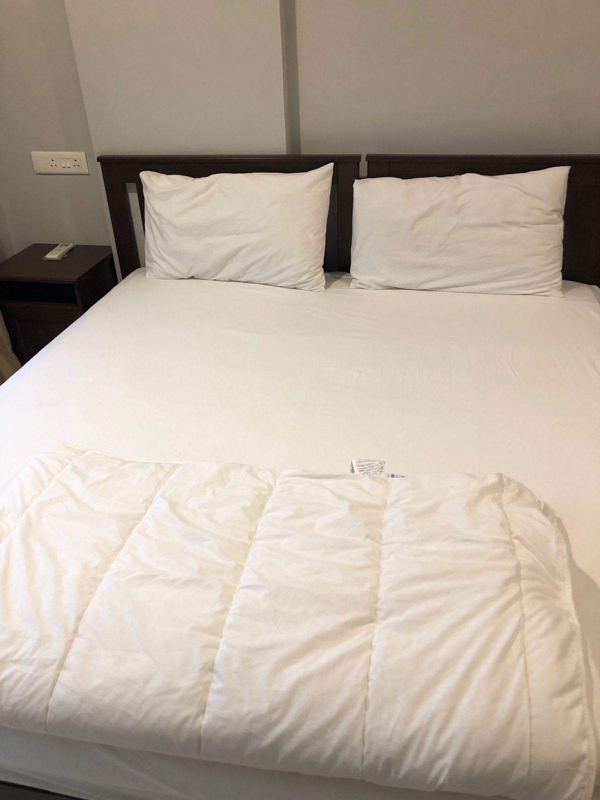 Una cama bien hecha con ropa de cama blanca y una colcha acolchada.