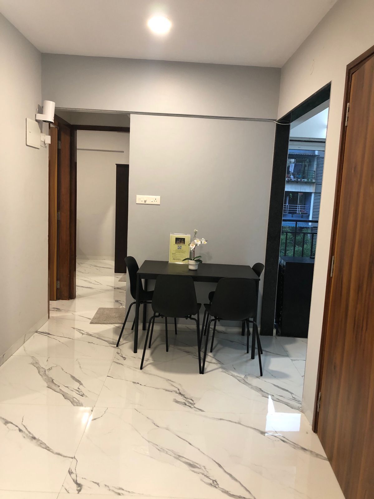 A modern dining area with a marble floor, a black table, and four chairs.