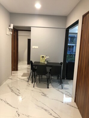 Un comedor moderno con suelo de mármol, una mesa negra y cuatro sillas.