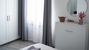 A bedroom with a bed, a dresser, a mirror, and a window with curtains.