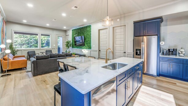 A modern kitchen with a marble island, blue cabinets, and a stainless steel refrigerator.