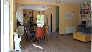 A spacious living area with a dining table, chairs, a sofa, and a bookshelf.