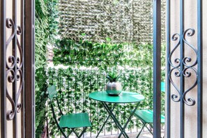 A balcony with a green table and chairs, surrounded by lush green plants. - Cosy apt near Duomo di Como (Como)