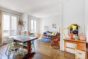 A spacious living area with a wooden dining table, chairs, a sofa, and a desk with drawers. - Appartement moderne à proximité du Marais (Unknown)