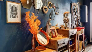 A room with a blue wall, a wooden dresser, a mirror, and various decorative items including a vase with orange flowers.