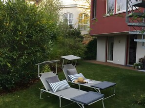 A garden with two lounge chairs and a small table, surrounded by greenery and a building with large windows. - Room 'Hortensie' with Private Terrace, Private Garden and Wi-Fi (Weil der Stadt)
