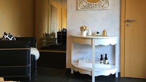 A room with a black leather sofa, a white console table with decorative items, a mirror, and a door. - Room 'Hortensie' with Private Terrace, Private Garden and Wi-Fi (Weil der Stadt)