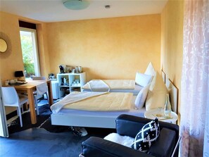 Quarto com cama, escrivaninha, poltrona, sofá e mesa de cabeceira com abajur.