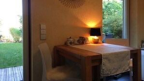 A room with a wooden table, a chair, a lamp, and a wall-mounted mirror. - Room 'Hortensie' with Private Terrace, Private Garden and Wi-Fi (Weil der Stadt)