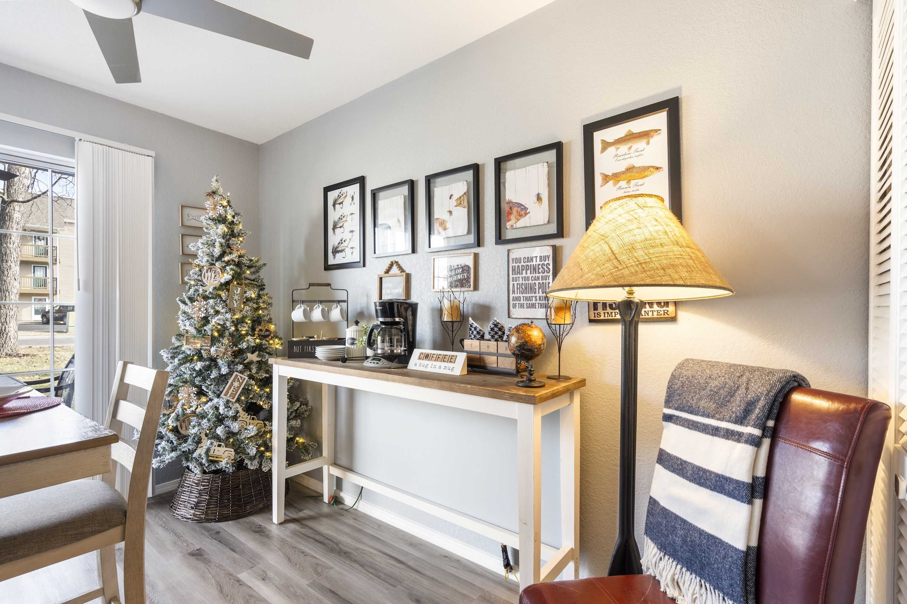 A cozy living room with a Christmas tree, a coffee station, and framed fish illustrations on the wall.