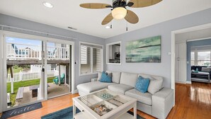 A spacious living room with a white sofa, a glass coffee table, and a ceiling fan. - Beautiful Home in Ocean Pines with Water Access for SUP's and Canoes (Ocean Pines)