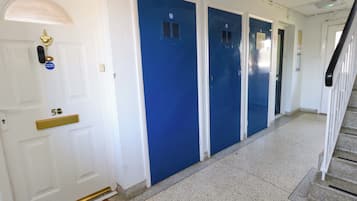 Um corredor com portas brancas e uma porta azul, um tapete de entrada e uma escadaria.