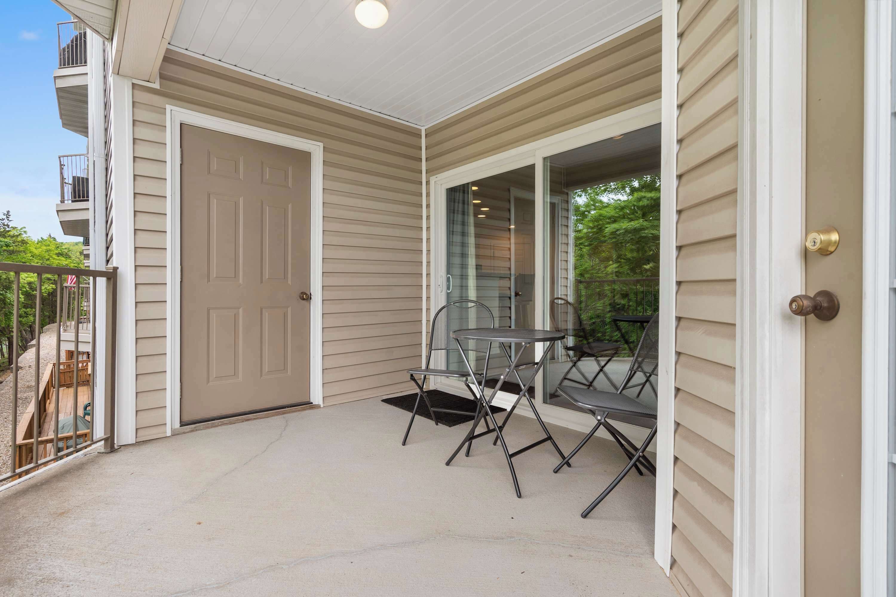 A covered porch with a sliding glass door, a small table, and two chairs.