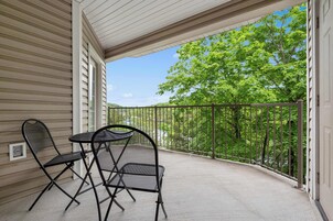 Un balcón techado con una mesa y sillas, con vistas a un paisaje verde y exuberante.