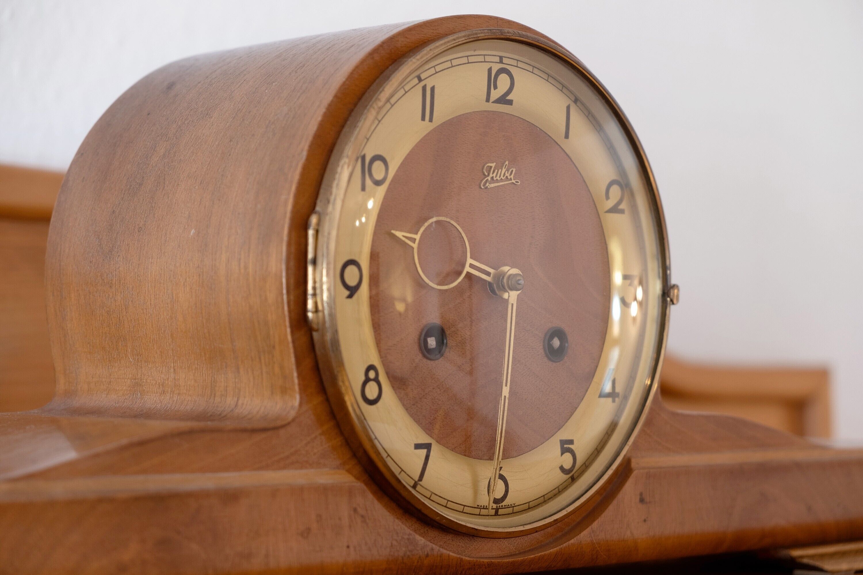 Un reloj de pie de madera con esfera circular y números romanos.