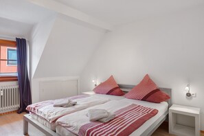 A bedroom with a bed, bedside tables, and a window with curtains.
