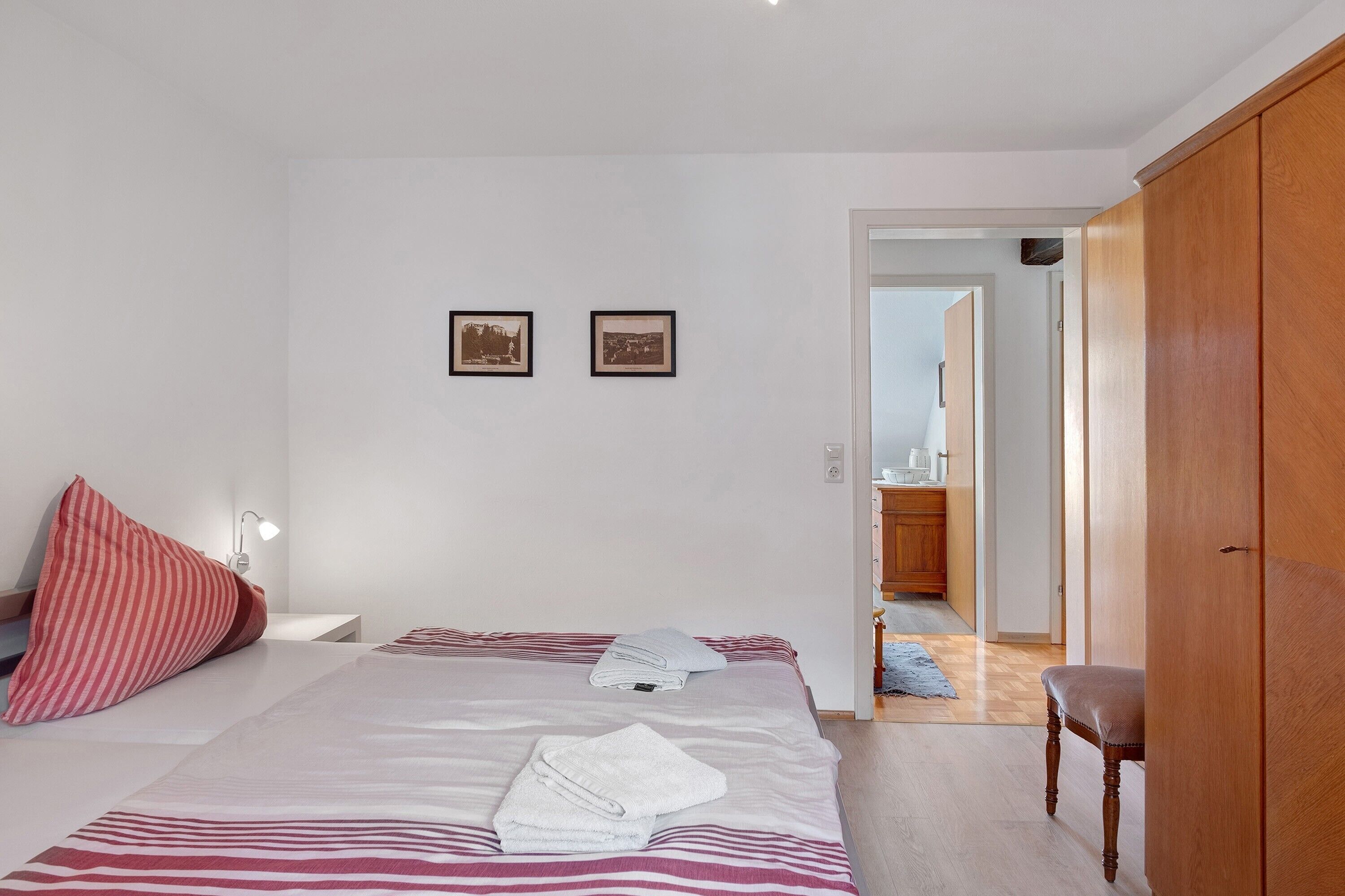 A bedroom with a bed, pillows, a bedside lamp, and a wooden wardrobe.