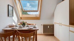 Un comedor con una mesa, sillas, un ventanal y un radiador.