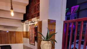 A reception desk with a wooden and white design, a Buddha head sculpture, and a potted plant. - Majestic Manor (Gorakhpur)