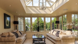 A spacious living room with two sofas, a coffee table, and large windows offering a view of the outdoors.