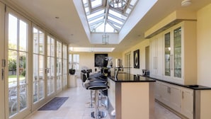 A spacious kitchen with a central island, large windows, and a skylight.