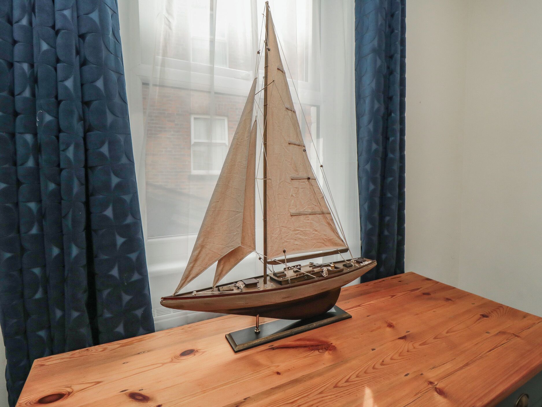 Een modelzeilschip op een houten tafel.