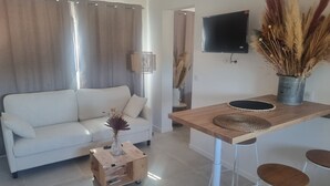 A modern living room with a white sofa, a wooden coffee table, and a TV mounted on the wall. - Villa Mané with swimming pool (Ollioules)