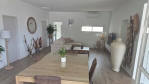 A spacious living room with a wooden dining table, beige sofa, and a large vase. - Villa Mané with swimming pool (Ollioules)