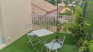A patio with artificial grass, a table, two chairs, and a large umbrella. - Villa Mané with swimming pool (Ollioules)