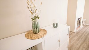 A white console table with a woven placemat, a vase with dried flowers, and two candle holders. - Close to Lisbon & Beaches (Amora)
