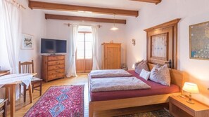 A bedroom with a bed, a TV, a wooden dresser, a desk, and a chair. - Schweizerhof am See  (Altmuenster)