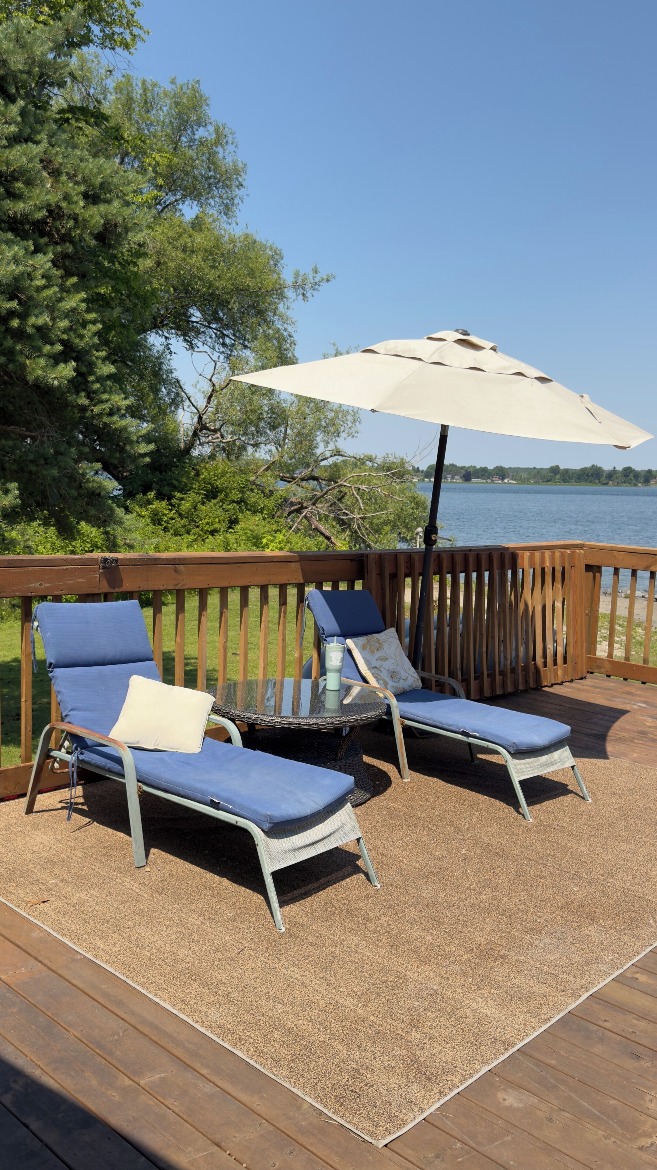 Une terrasse avec deux chaises longues, une table et un parasol.