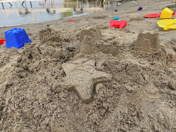 A sandy beach with various sandcastles and toys.