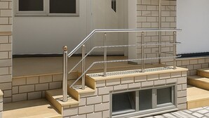 A modern building entrance with a staircase, a door, and two air conditioning units mounted on the wall. - Sasori Apartments (Sarande)