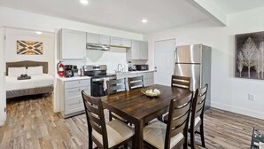 A compact kitchen with white cabinets, a dining table with four chairs, and a refrigerator. - Serene Escape - Peaceful 3-BD Retreat with Yard (Grand Prairie)
