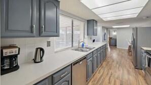 Una cocina moderna con gabinetes grises, una cafetera y un lavavajillas.