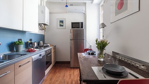 Una cocina moderna con electrodomésticos de acero inoxidable, armarios de madera y un comedor con una mesa preparada para dos personas.