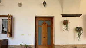 Une porte en bois avec un panneau de verre, une plante en pot, un banc et un paillasson.