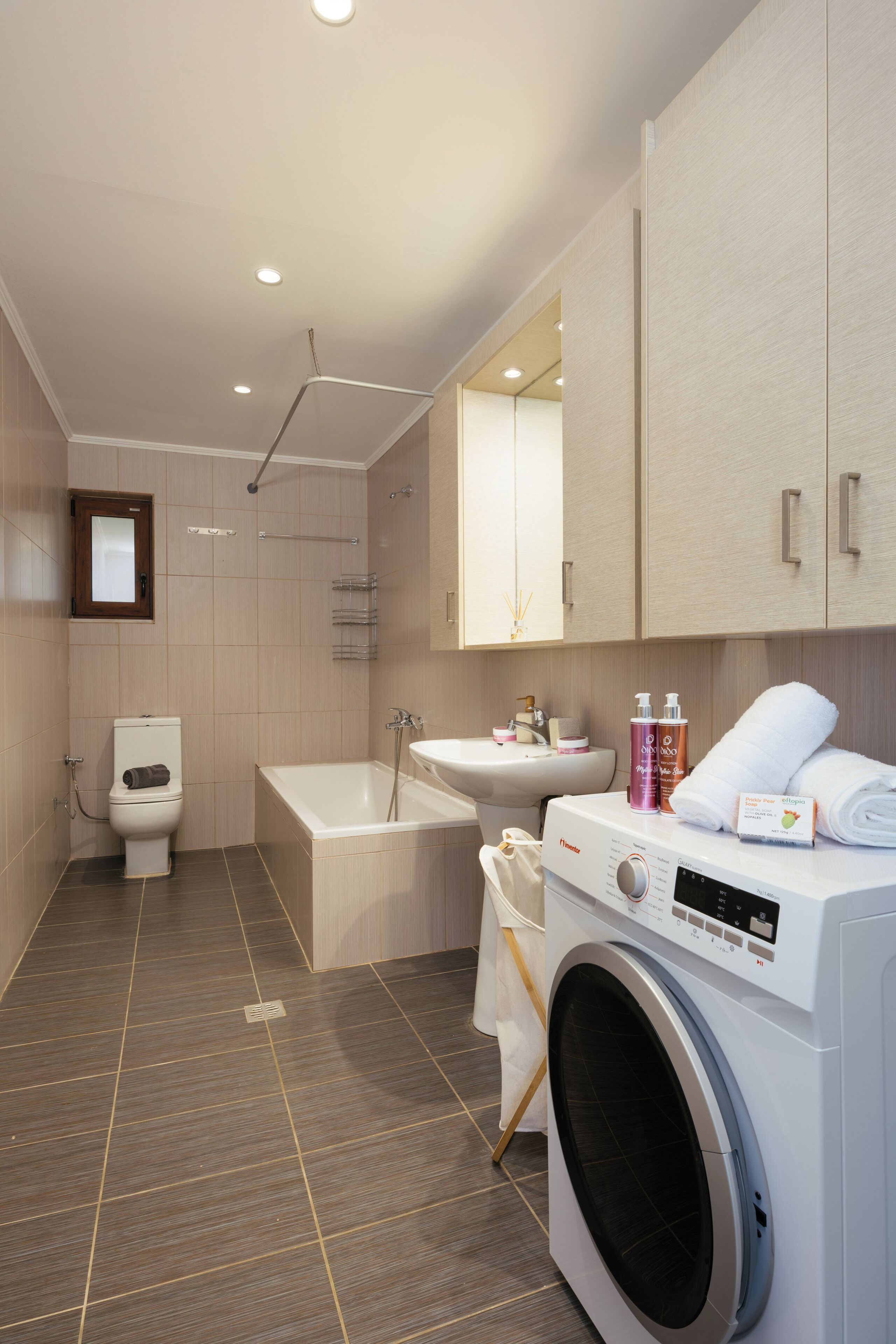 A modern bathroom with a toilet, sink, bathtub, and washing machine.