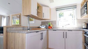 A modern kitchen with wooden cabinets, a built-in microwave, and a window providing natural light.