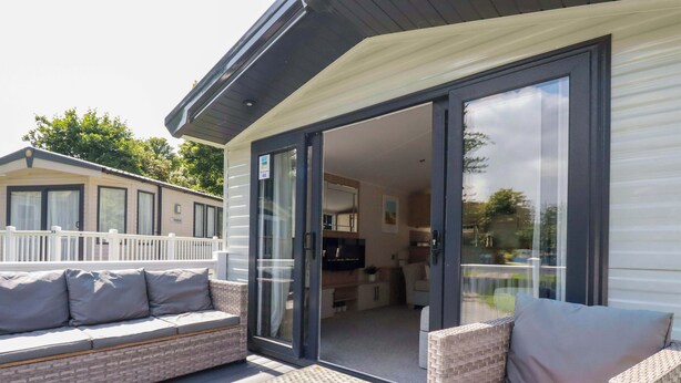 A covered outdoor seating area with wicker furniture and a glass door leading to an interior space.